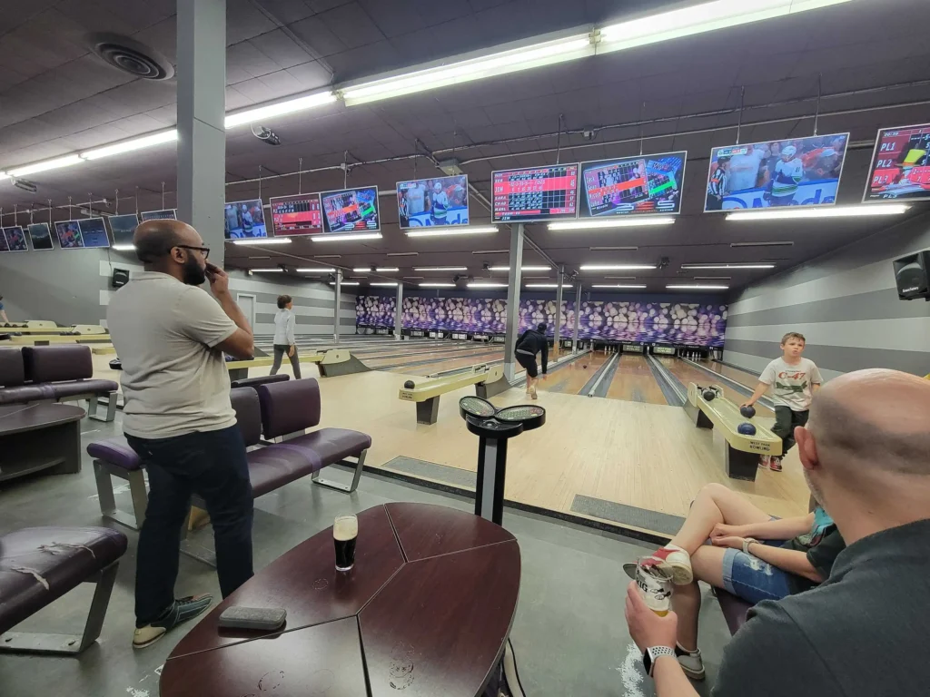 Marlon watching Jim taking his turn at a team bowling social event